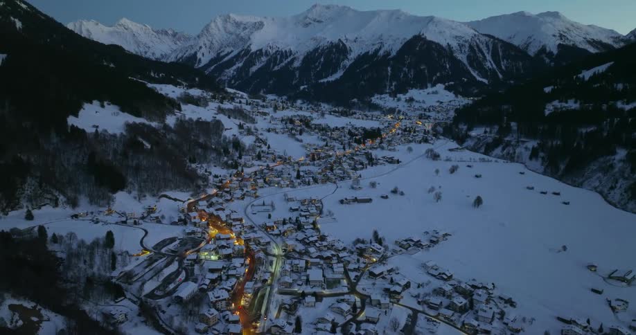 Cars driving in a small rural town at the base of a mountain range