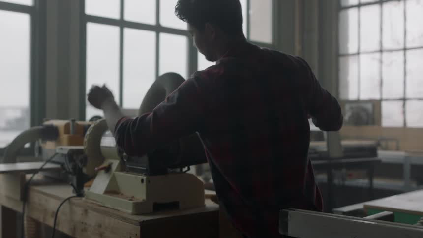 Man walks to sanding machine and starts sanding a piece of wood