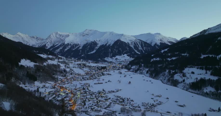 A small town in a snowy valley between mountains on a clear day