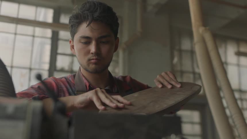 Man smooths a piece of wood in a workshop