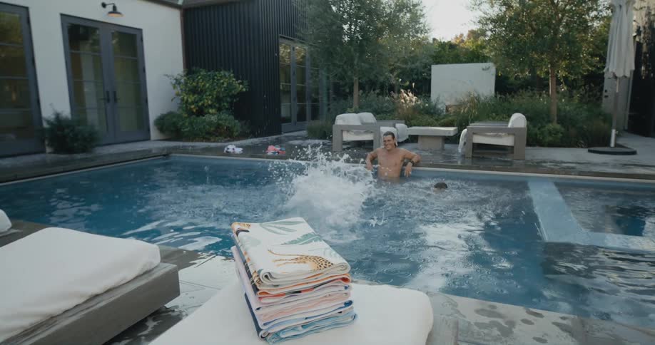 Boy jumping into swimming pool as father and sister watches