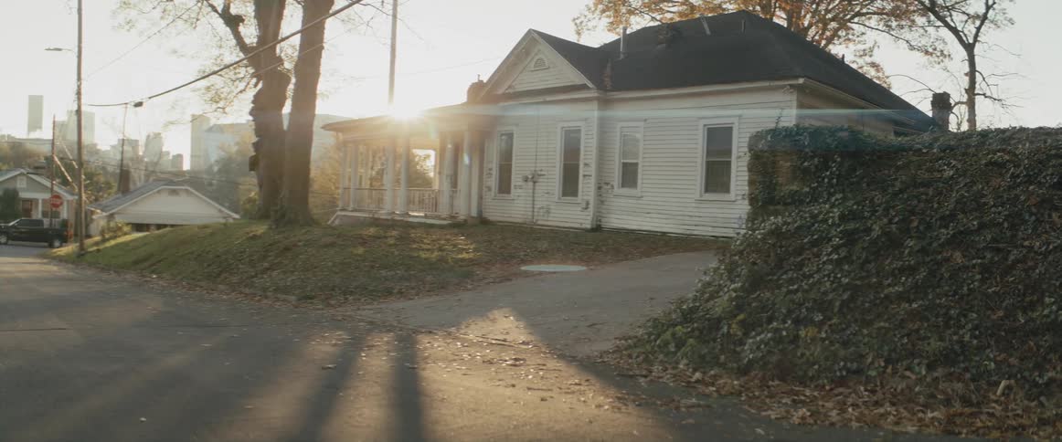 A small white house in a residential neighborhood on the outskirts of a city