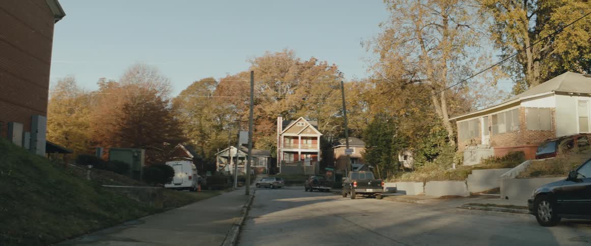 Neighborhood with trees in fall colors and automobiles are parked on the side of the street