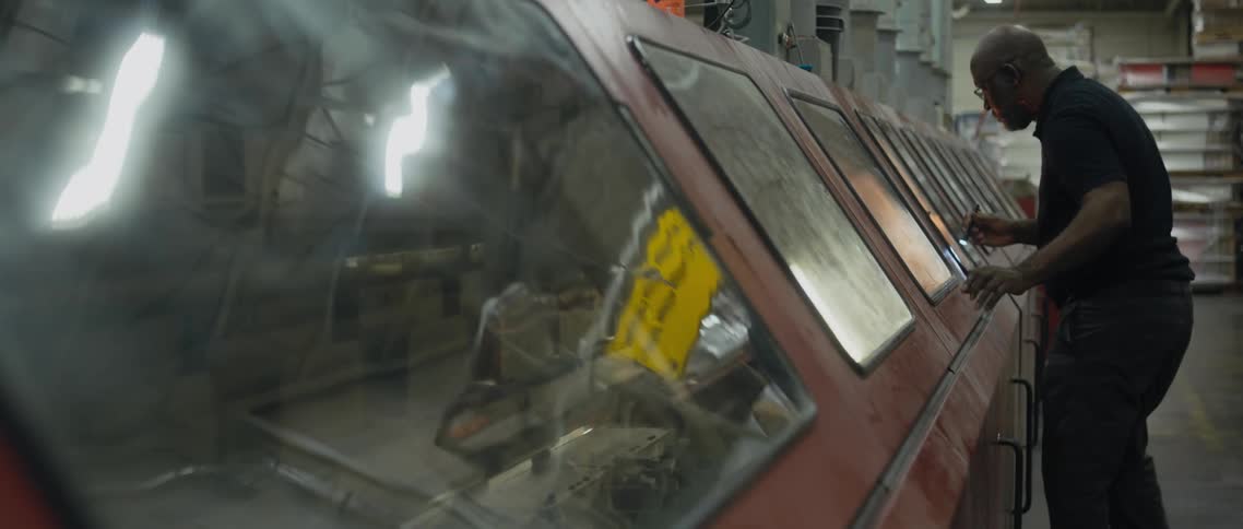Man move along long enclosure covering conveyor belt in factory examining surface with small flashlight