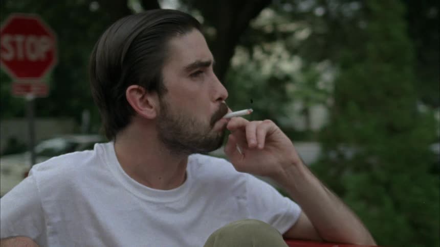 A man is in the back of a moving truck smoking a cigarette