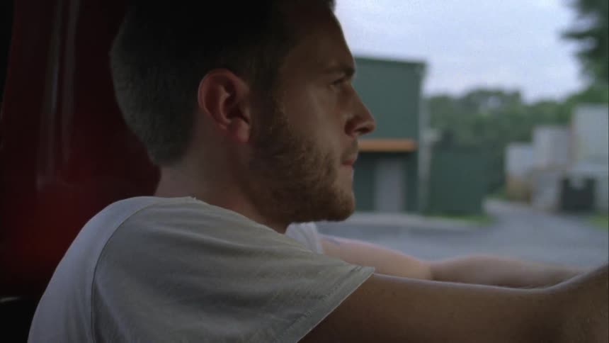A man drives a pickup truck through a rural town