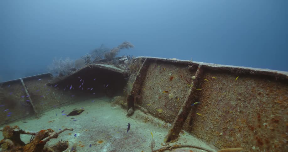Deck of a sunken ship underwater in the over the sand in the bottom of the blue ocean