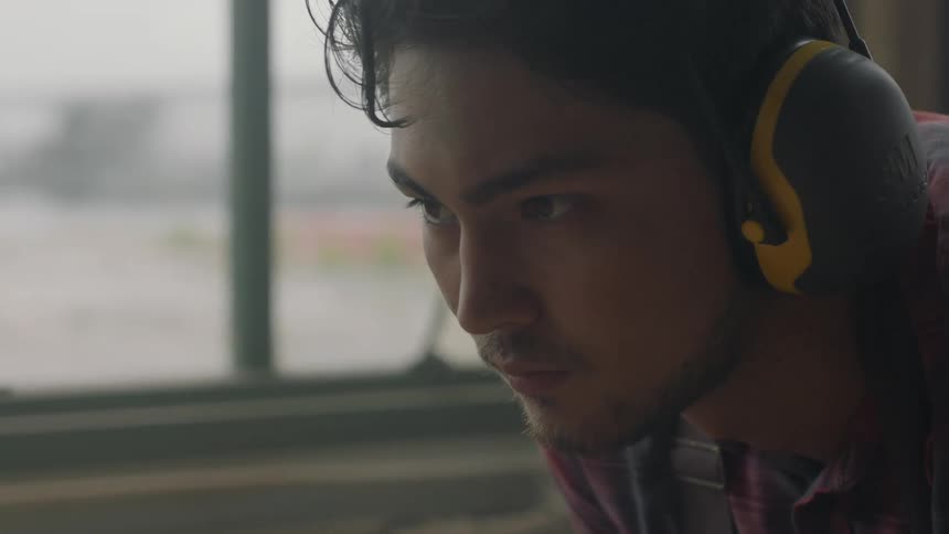 A man wearing headphones is leaning forward
