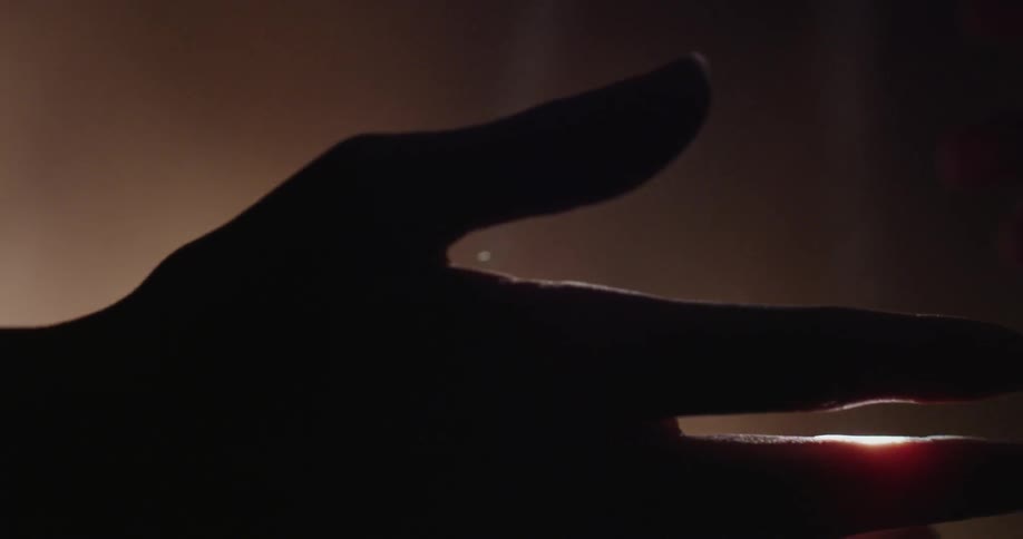 The hands of two people touching under rays of sunlight