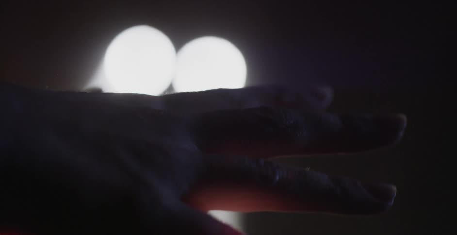A hand plays in a beam of light