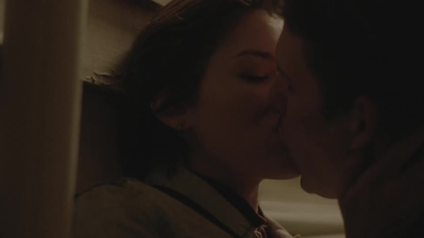 Couple kissing next to a wall