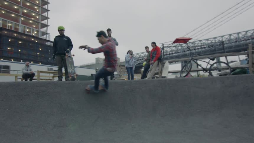People watch as a skateboarder rolls by at a city skatepark