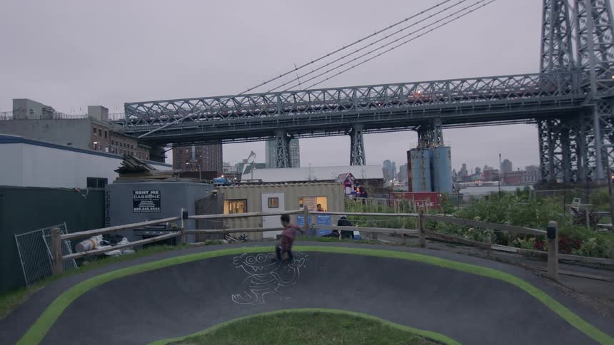 A man is skateboarding around a rink by a bridge