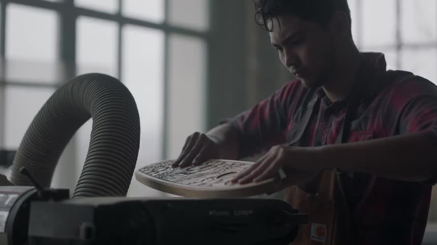 Man smoothes a piece of carved wood in a workshop