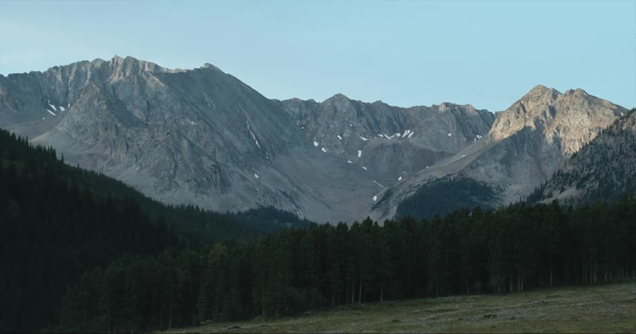A forested mountain with a mountain ridge in the distance
