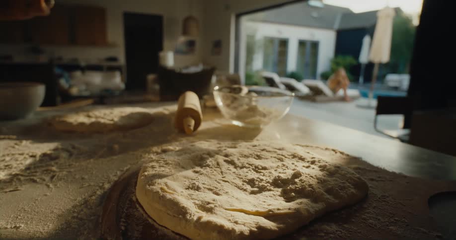A person preparing a pizza at the kitchen counter inside the house