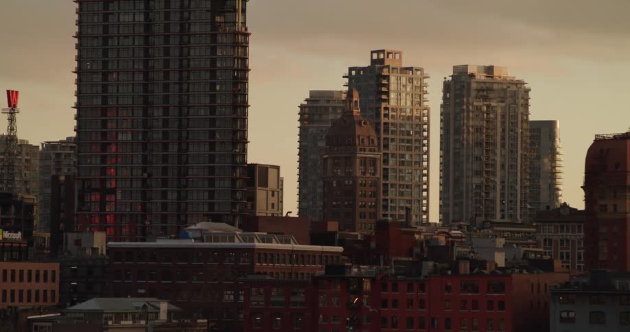 Birds fly across a sunset skyline of Vancouver's Gastown area