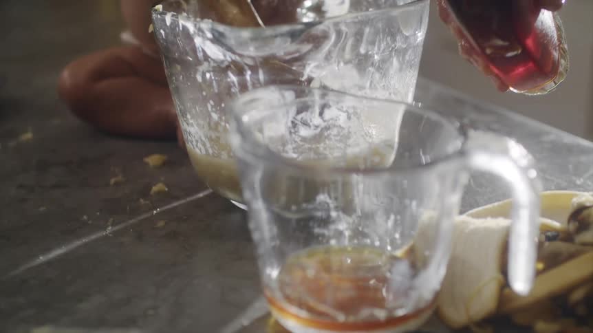 A man pours liquid into a measuring cup while baking at home with his baby