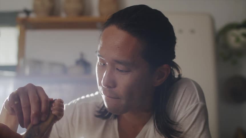 A man has his infant help him mix food in the kitchen