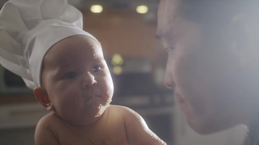 Father kissing babys chubby cheeks covered in batter