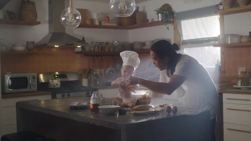 Asian man taking care of his baby son and cooking in a kitchen counter