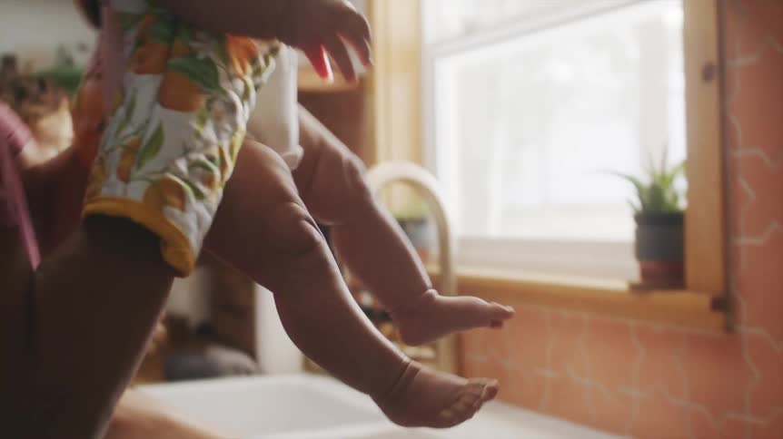 Man wearing cooking gloves picking up his baby son from the kitchen counter
