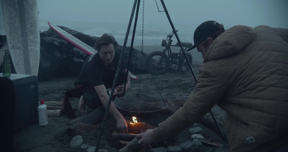Two men lighting a campfire at the beach