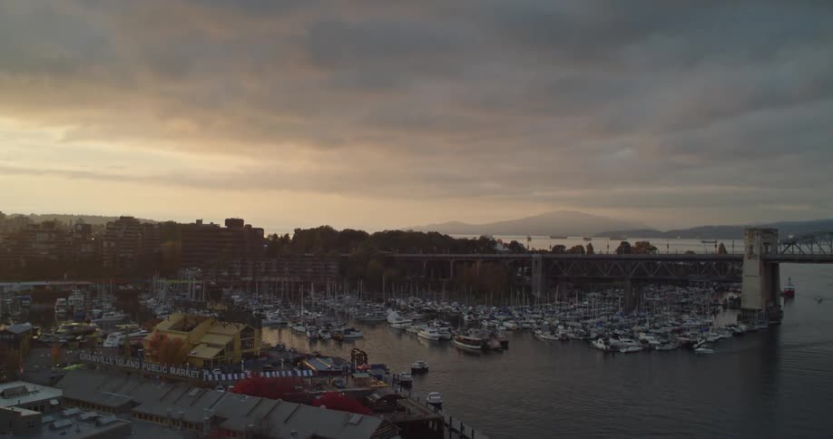 Boats in a seaside marina by the Burrard Bridge on a stormy sunset evening