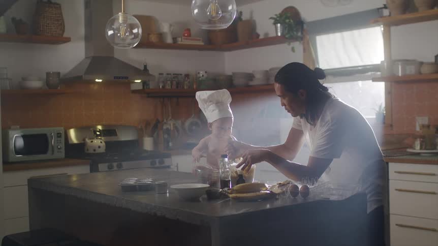 Asian man cooking with his baby at a kitchen counter
