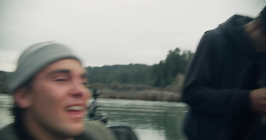 Two friends in a camping site by the river drinking talking and laughing together