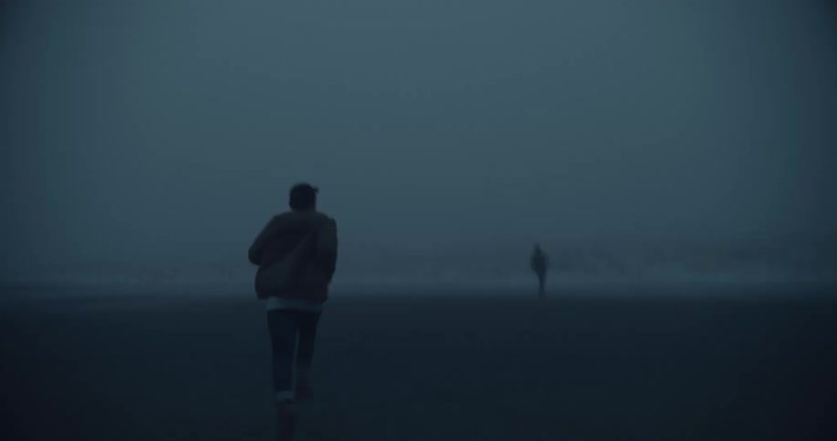 Two men running around at the beach during a foggy day