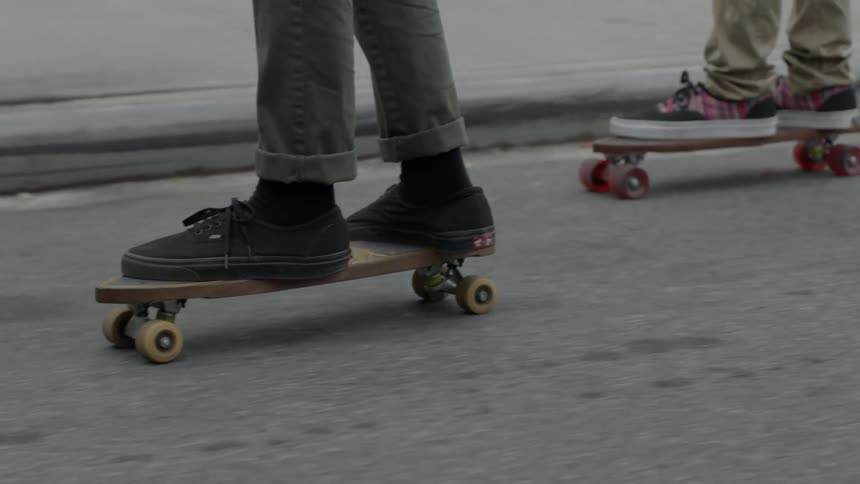 Two people skateboarding on a city street