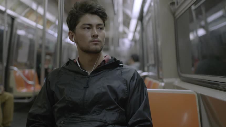 A man is sitting on a train looking out the windows