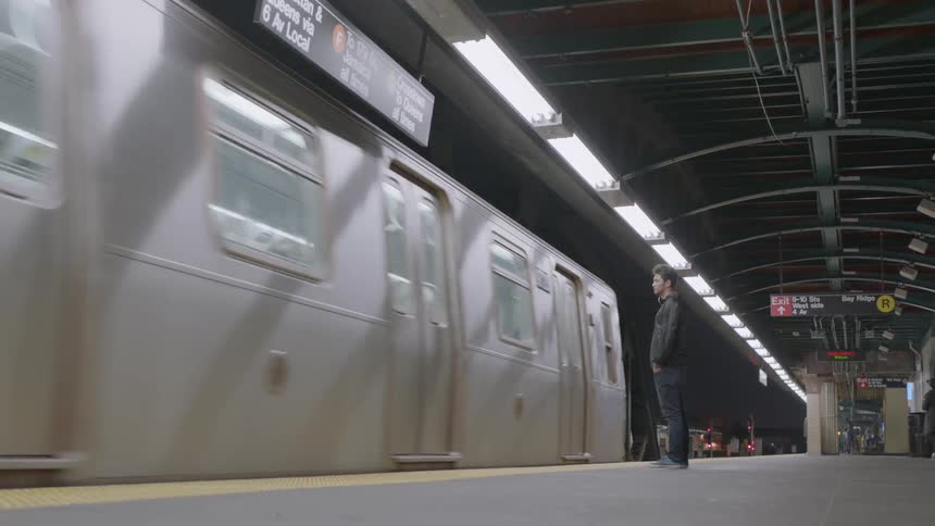 Man standing in subway as train passes by