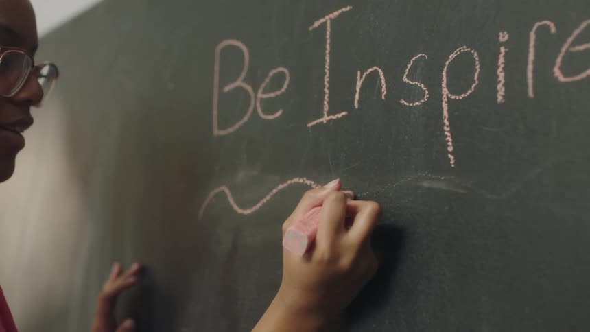 Female student underlines inspirational saying written on blackboard