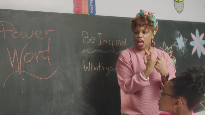 Female teacher with pink sweater teaches students about inspiration and power at school