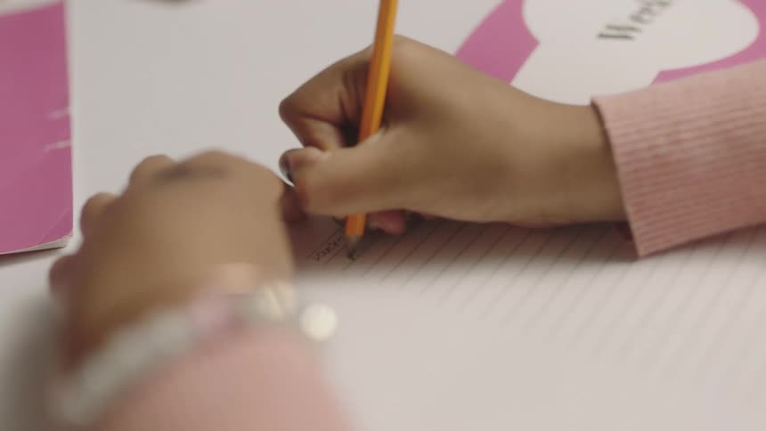 A child uses a pencil to write in a notebook