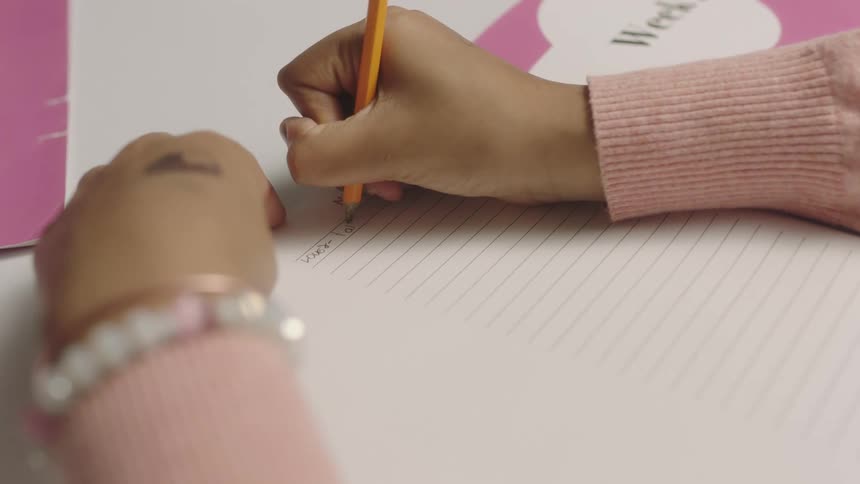 A girl uses a pencil to write in a notebook