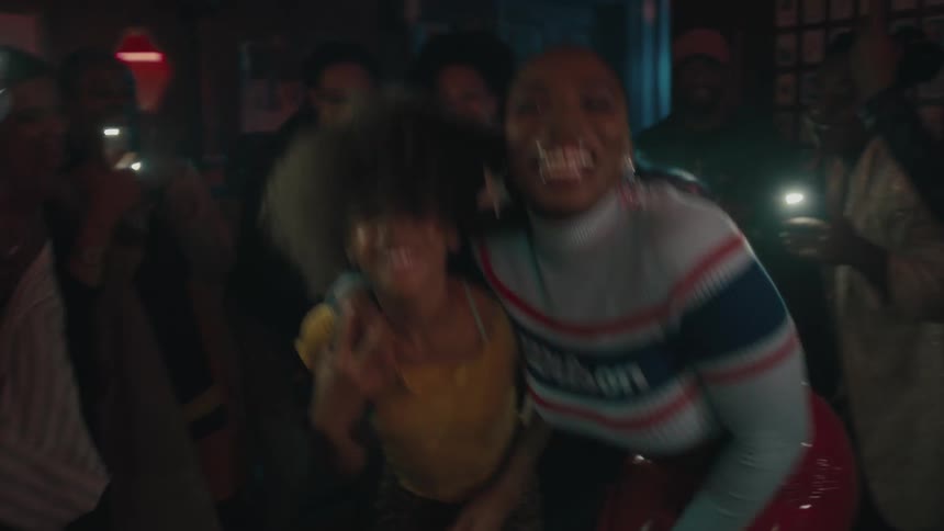 People hold up phones with flashlight on as others dance at party