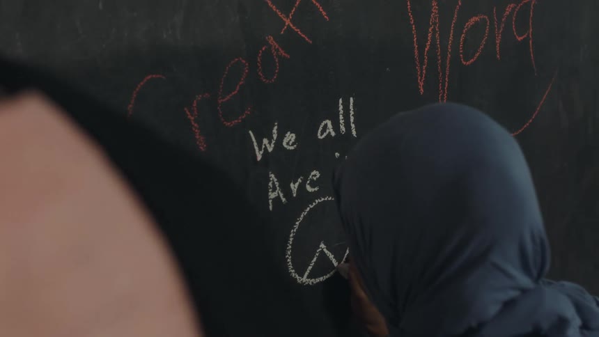 A person is writing symbols on the chalkboard