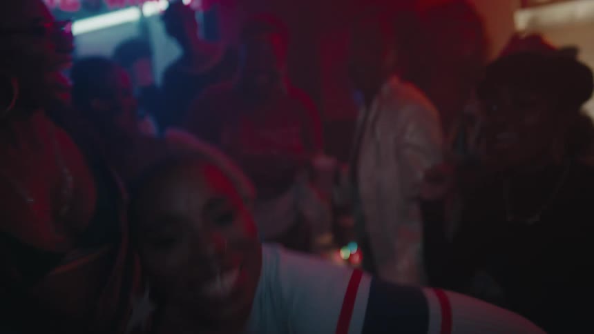 A group of friends dance and laugh in a bar