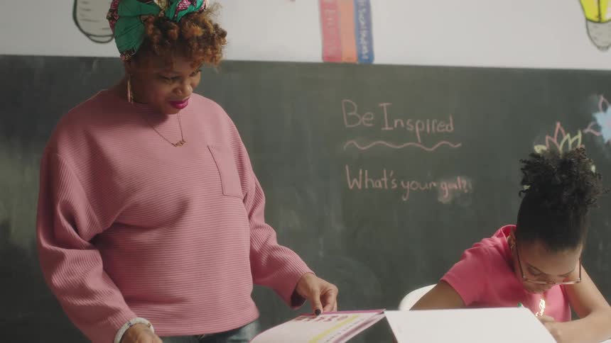 A teacher smiles while flipping through her students artwork