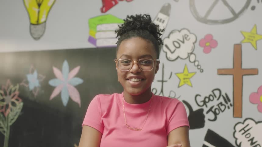 A woman is smiling by the chalkboard