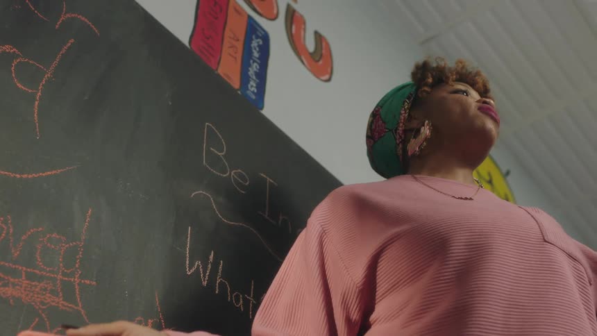 A teacher explains a lesson at the front of the classroom
