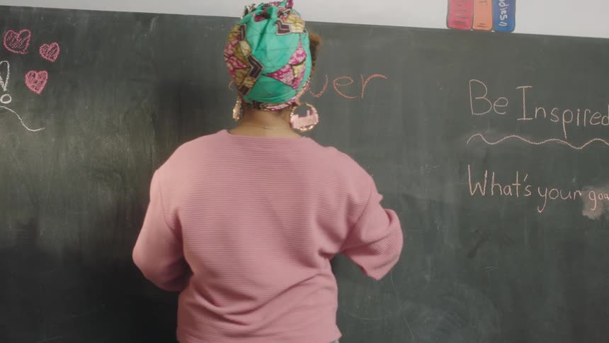 A teacher writes inspirational messages on a blackboard