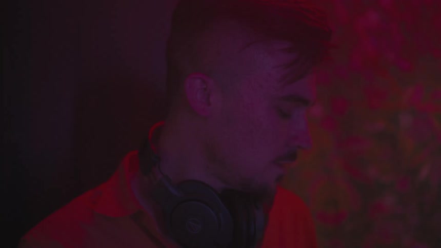 A man with headphones around his neck turns his head and looks away and then looks back