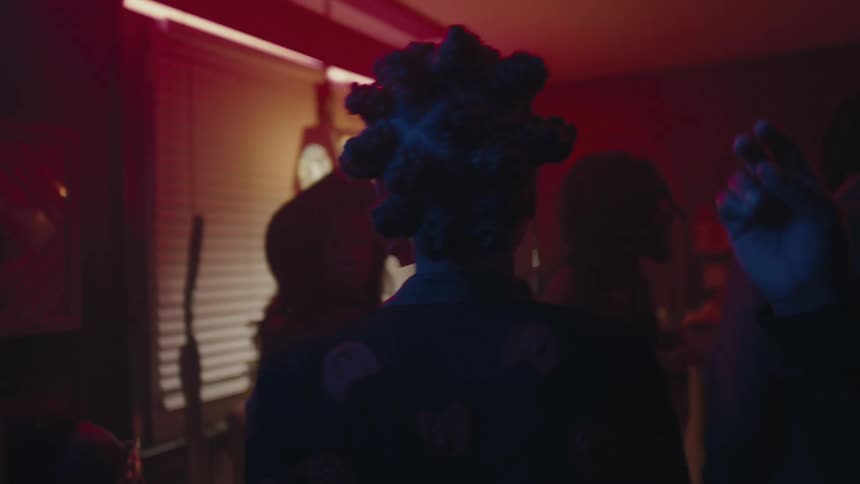 A woman walks through a crowded house party