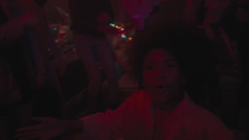 A young girl dances in the middle of a crowd in a dark club