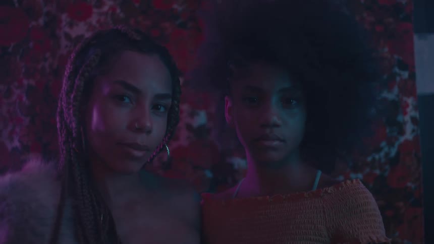 Two beautiful young black women pose for the camera in a darkened room