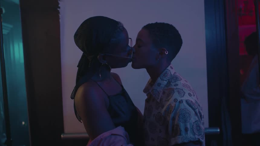 A teenage boy and girl hold one another and kiss